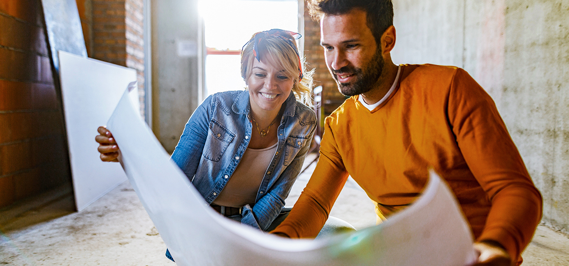 Couple looking over renovation plans on white sheet paper