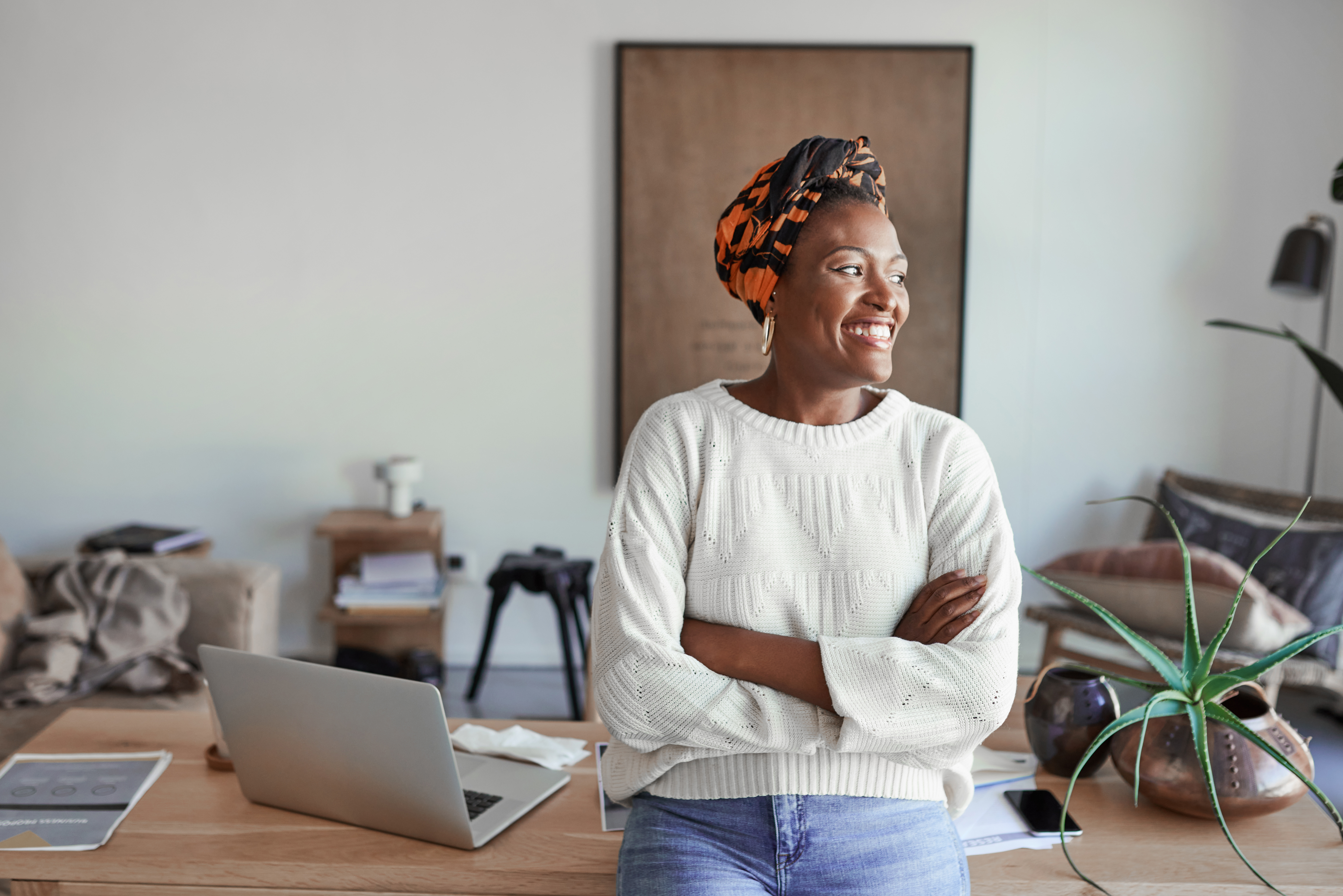 Woman Smiling while sitting on a desk with laptop