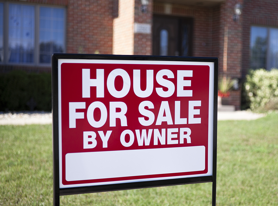 House for Sale By Owner sign posted on a front yard with green grass