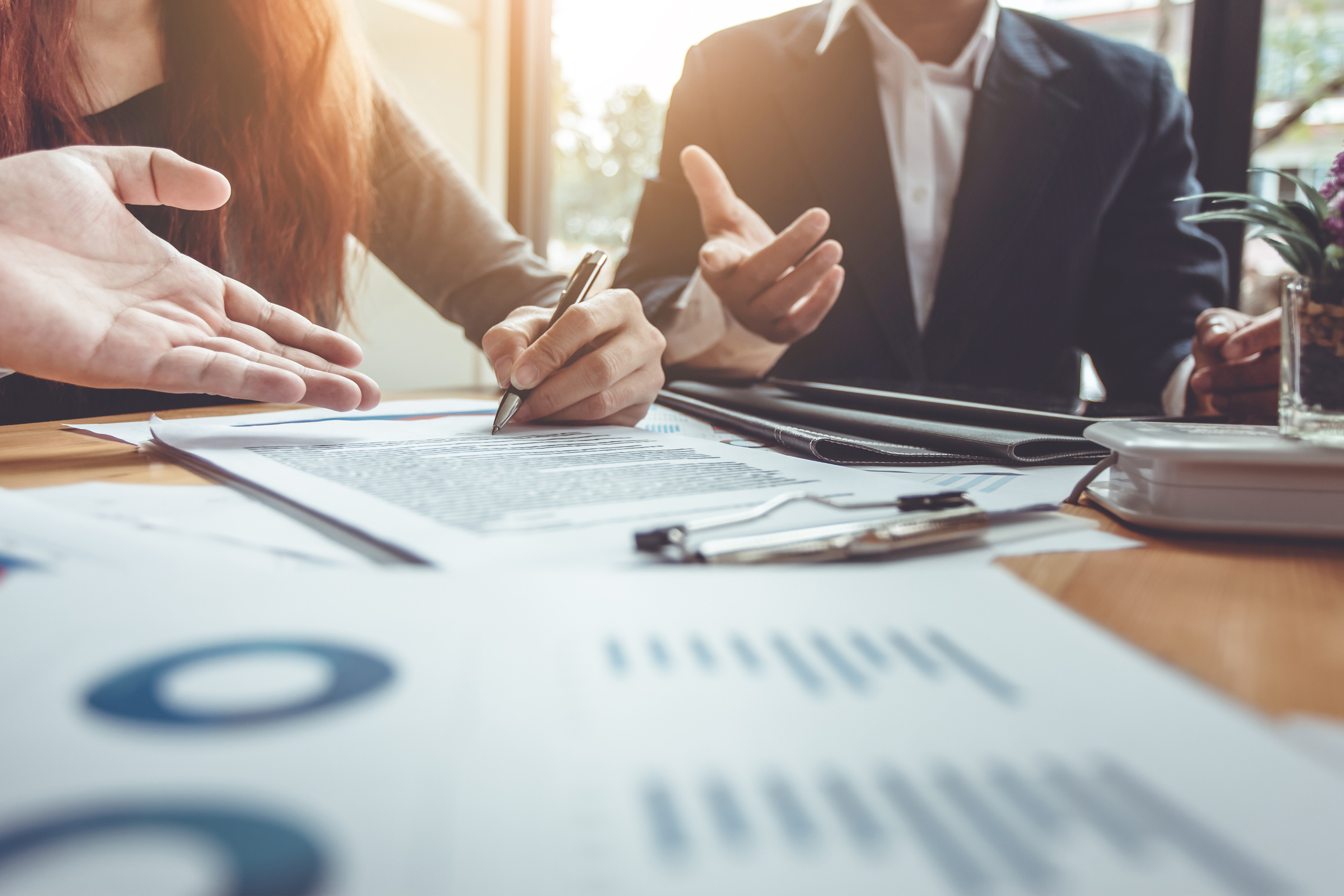 Woman signing a form while business person talks to her and other person