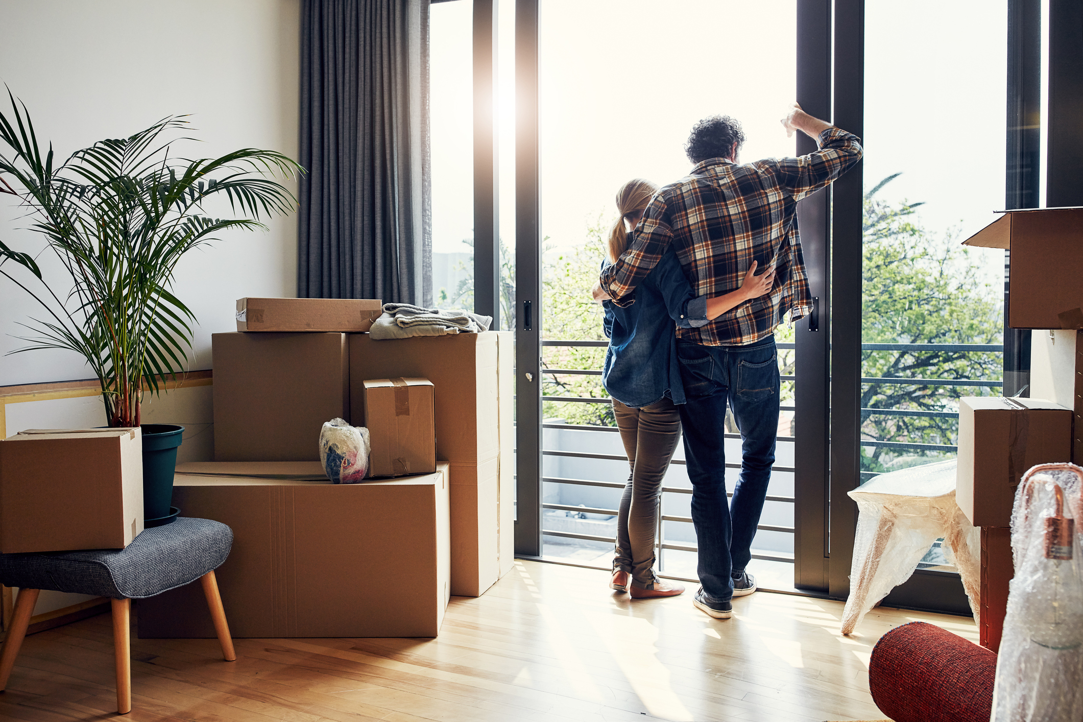Couple looking out of sliding glass doors with boxes around them