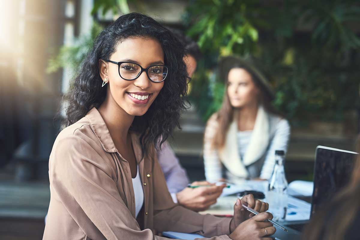 Woman smiling with two people at table in background