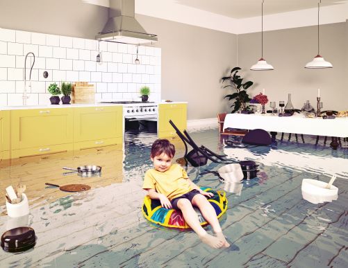 Little boy sitting in inner tube in kitchen full of water