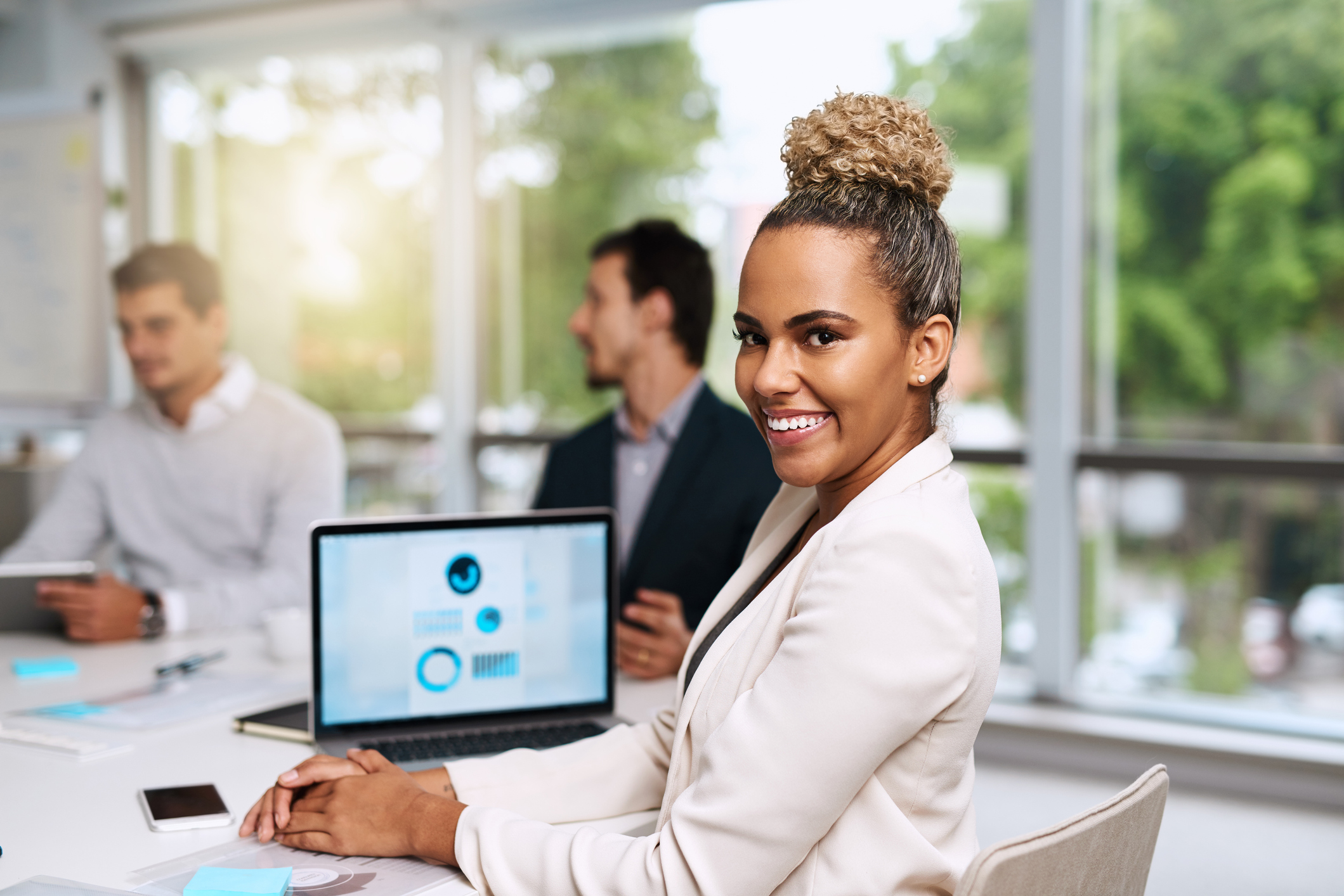 Woman at work in front of laptop screen with two men in background