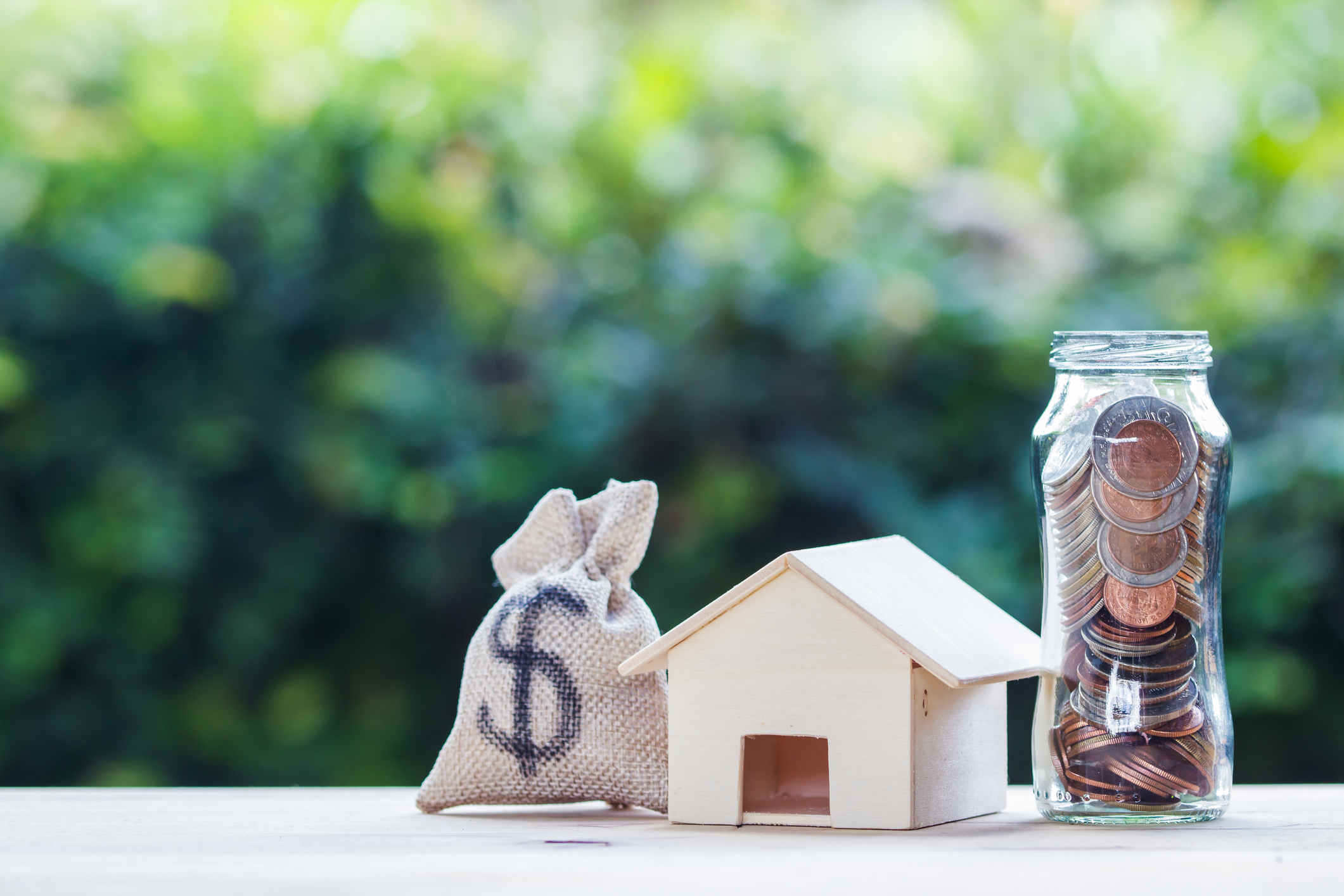 Money sack, clay house, and coin jar sitting on counter