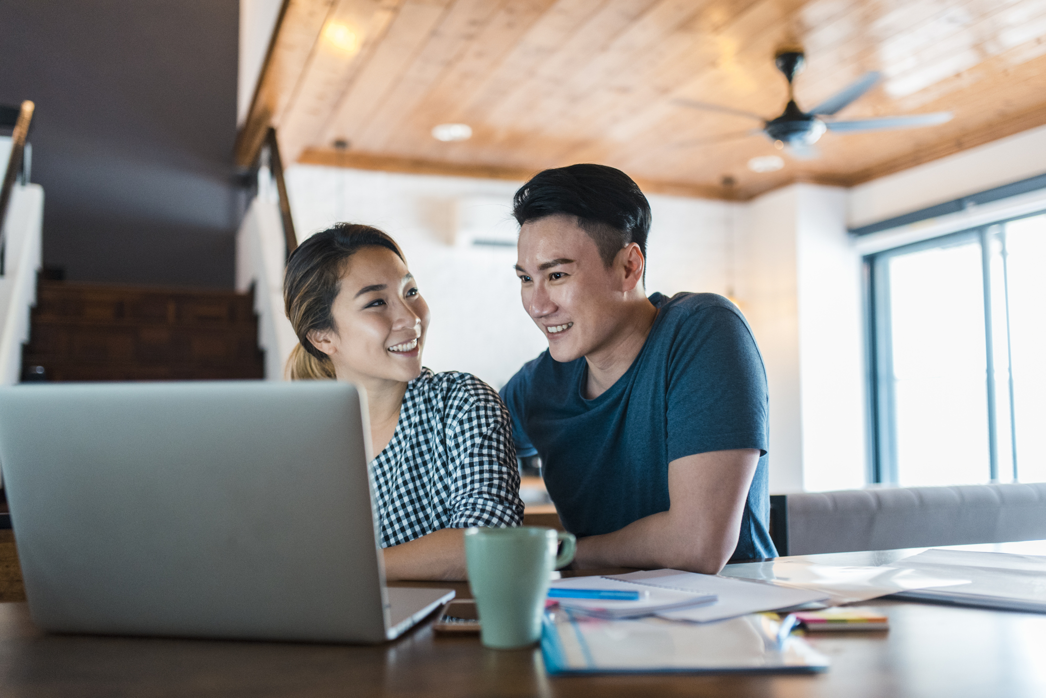 Couple looking at laptop with papers spread out on table