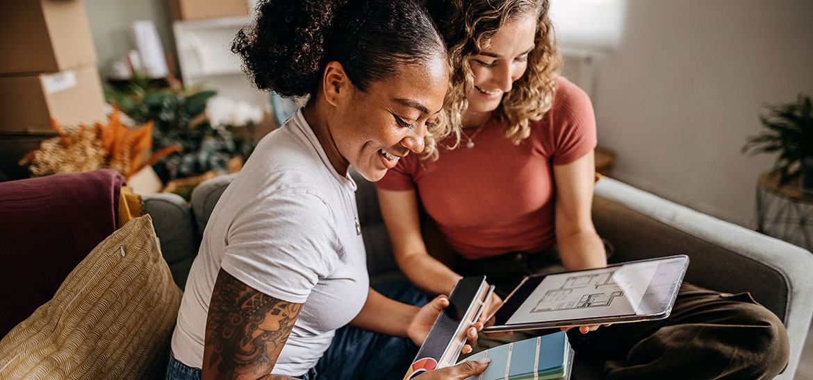 Two women looking over floorplans on an ipad while holding paint swatches
