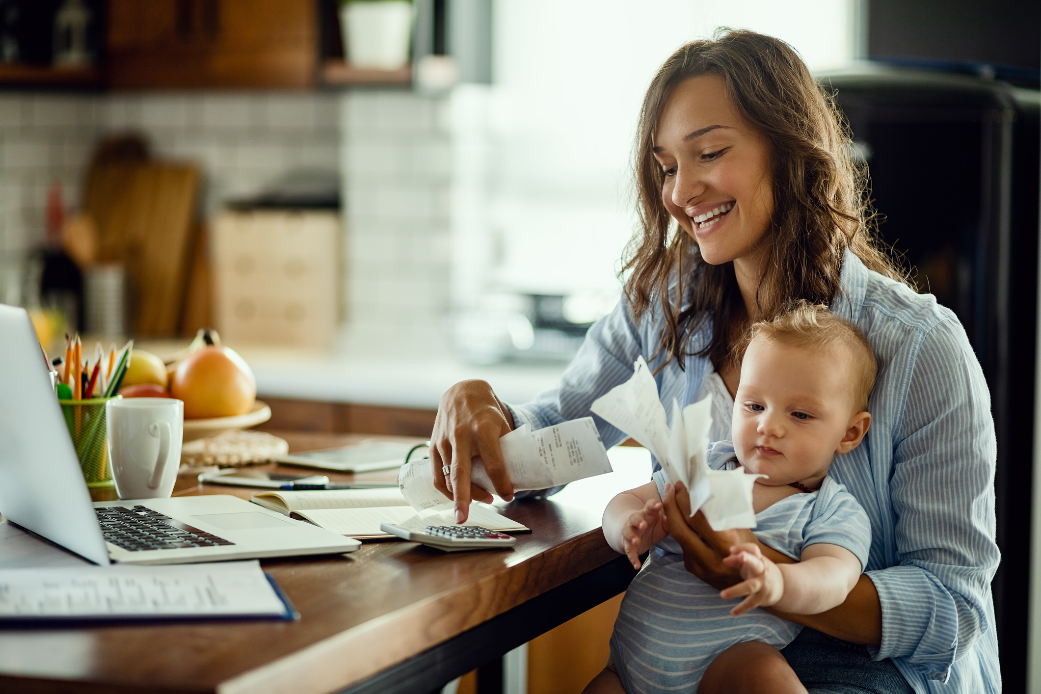 Mom with child using calculator and holding receipts