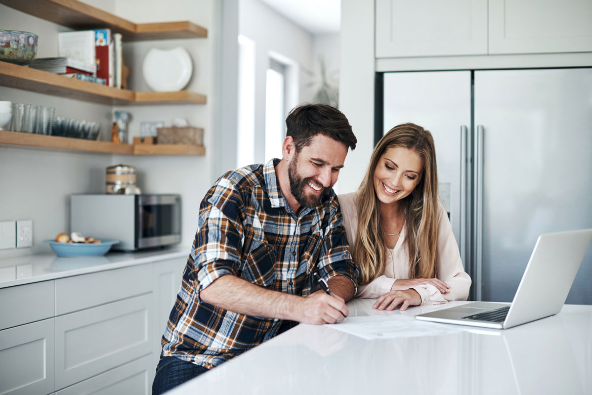 Couple at kitchen counter signing documents