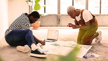 Two people looking at papers on floor